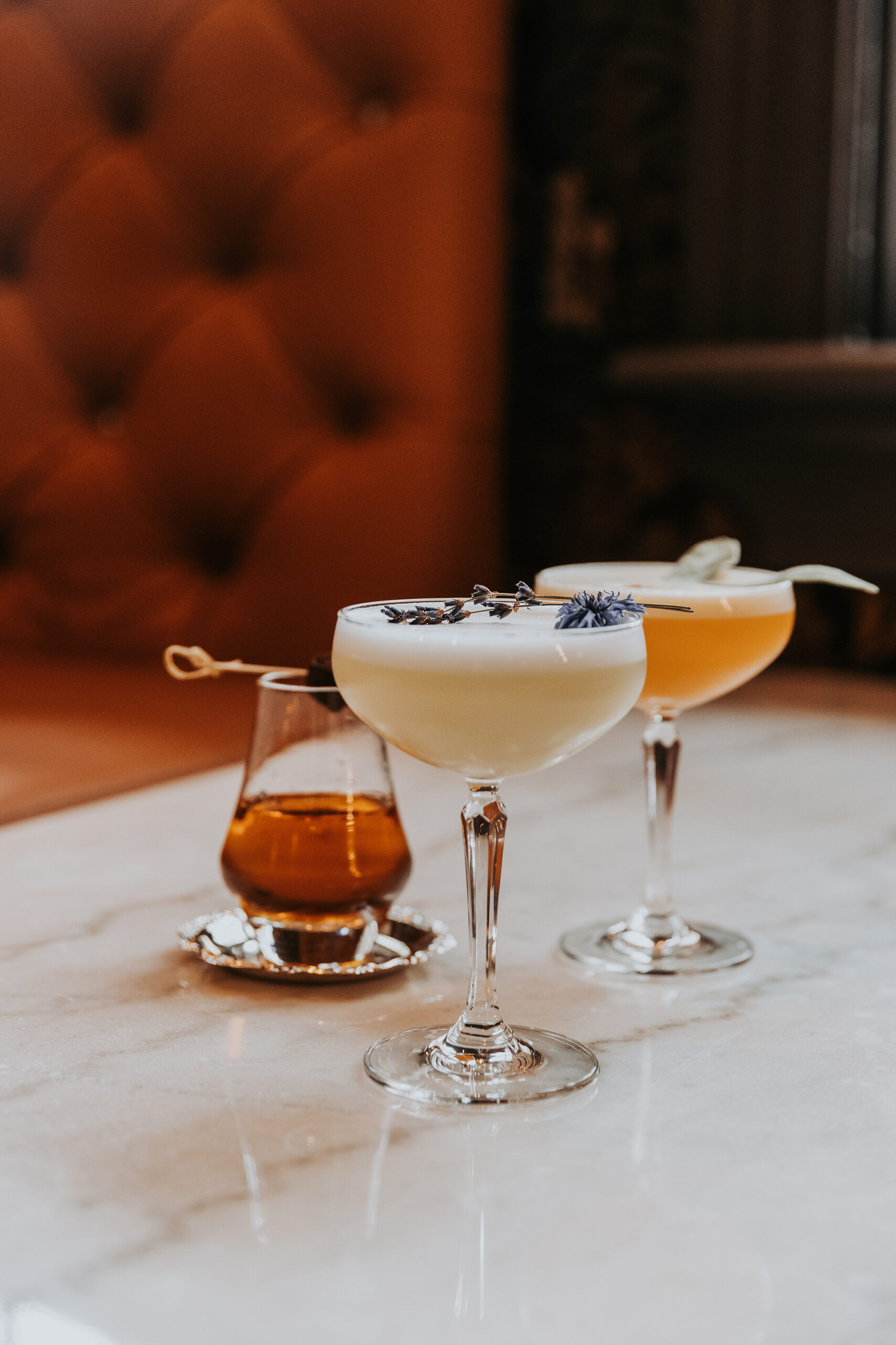 Trio de cocktails élégants sur comptoir en marbre avec banquette en cuir orange