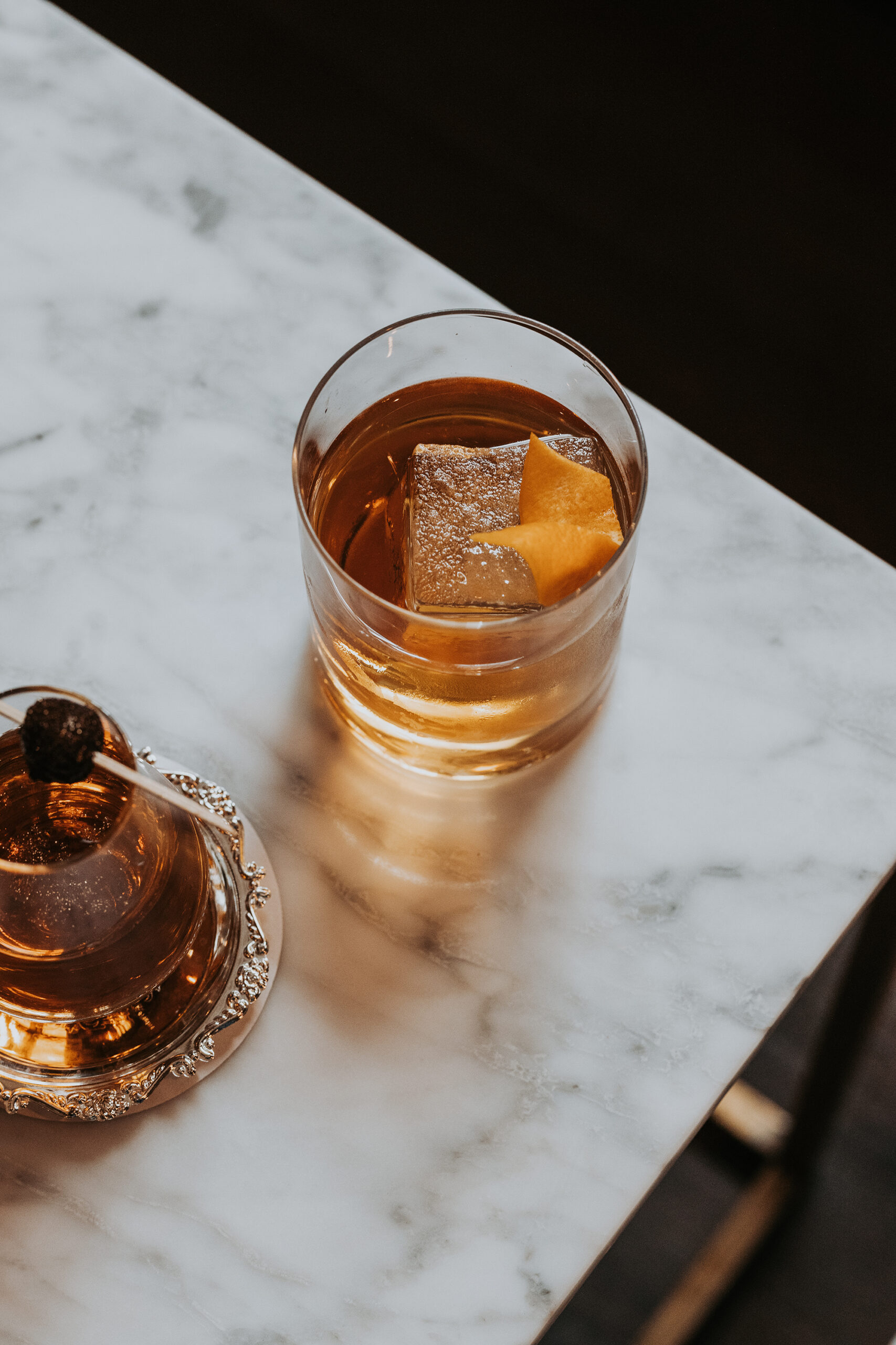 Verre de whisky old fashioned avec glaçon carré sur comptoir en marbre blanc