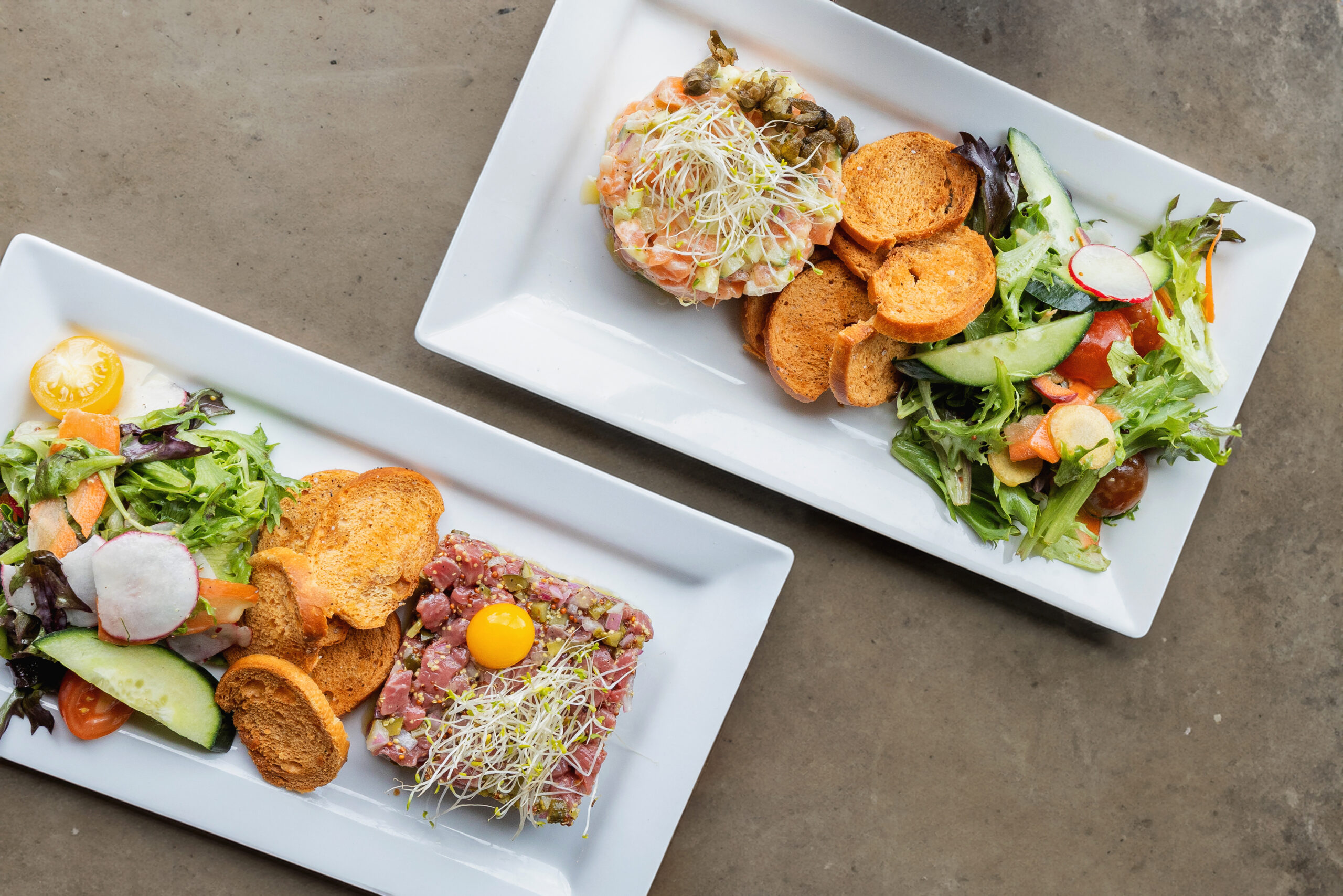Deux assiettes de tartare gastronomique avec crostinis salade et légumes frais vue du dessus