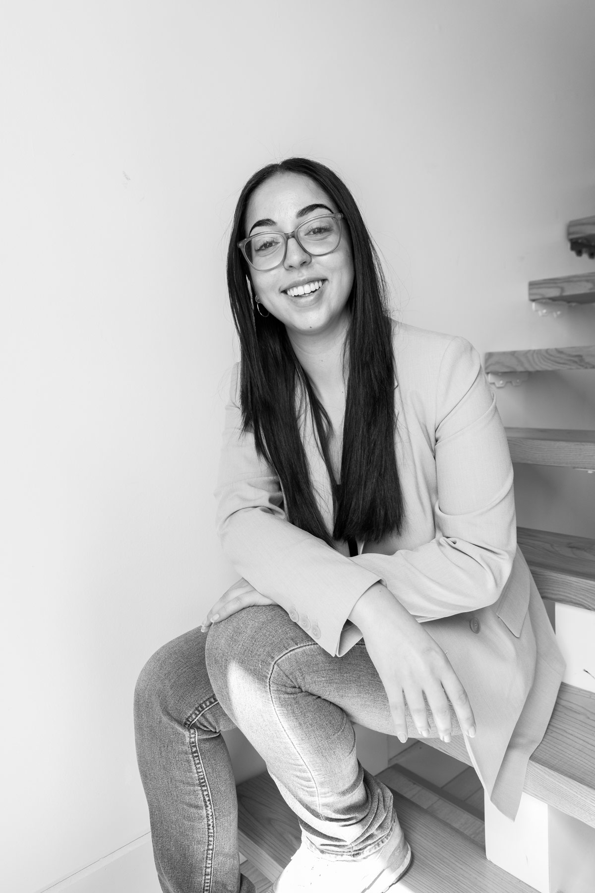 Portrait professionnel noir et blanc de Mouna membre de l'équipe Solutions M avec lunettes et blazer
